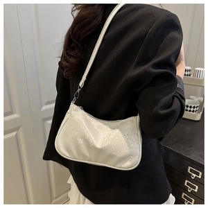 Close-up of white faux snake pattern shoulder bag worn with a black blazer