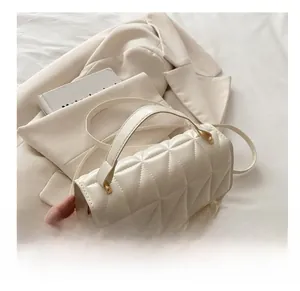 Detailed close-up of cream quilted square handbag with handle and crossbody strap detail