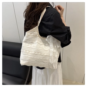 Détail du sac cabas en dentelle blanche avec motifs floraux et nœud décoratif