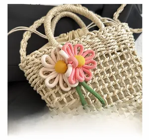 Detail of woven straw bucket bag showing handmade texture and floral charm