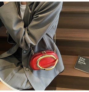 Detail showing red glossy handbag with gold ring buckle and elegant metal chain strap