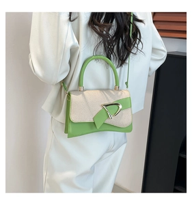 Detail of green and beige crossbody bag with gold D-buckle on white suit background