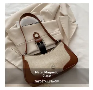 Detail shot of the crescent bag's magnetic hardware buckle on leather and canvas texture