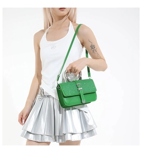 Close-up of green leather handbag with sparkling sequins and silver U-shaped metal handle