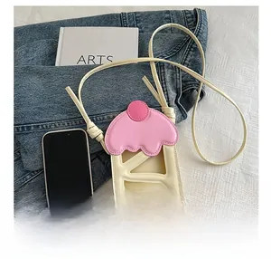 Detail view of pink and white cupcake style phone crossbody bag next to a smartphone