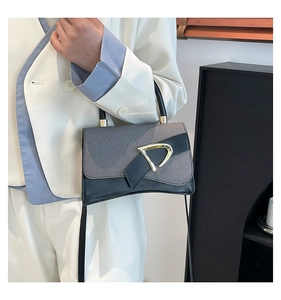 Detail of color-block crossbody bag with grey fabric, black leather, and gold D-ring buckle