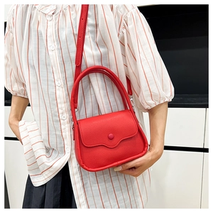 Detail of red lychee grain leather mini bag showing round handle and crossbody strap