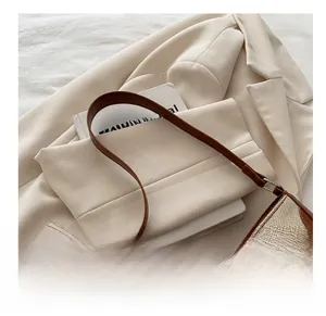 Close-up of cream woven crescent bag with brown leather trim and metallic buckle detail