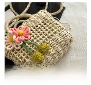 Detail of hand-woven beige straw bag featuring 3D floral accents and drawstring closure