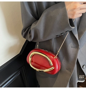 Detail of red leather evening bag with large gold metal ring and chain strap