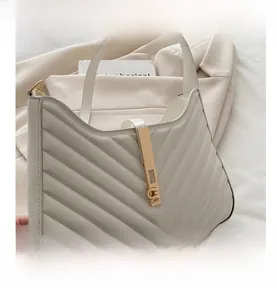 Detail of V-quilted faux leather shoulder bag featuring a gold metal buckle and strap
