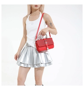 Detail of red leather handbag with sequined flap and silver metal handle worn by a model