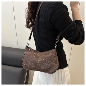 Detail view of brown snakeskin pattern shoulder bag worn by model in minimalist setting