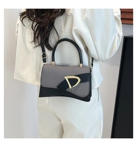 Detail of grey fabric and black leather contrast with golden D-ring buckle on handbag