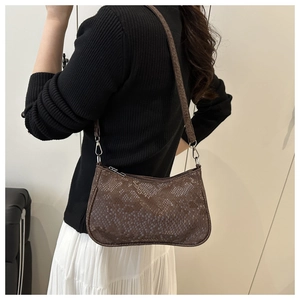 Detail of brown snakeskin pattern and silver metal hook on the crescent-shaped bag