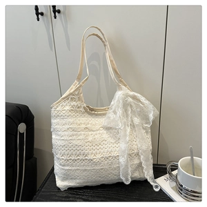Détail d'un sac cabas en dentelle blanche avec couches florales et grand nœud latéral
