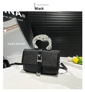 Detail of black crossbody bag with shimmering flap and irregular silver metal handle