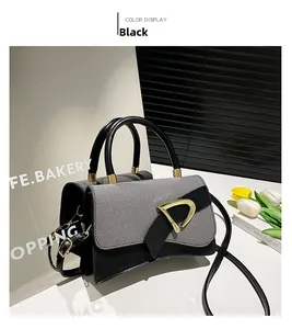 Detailed close-up of retro black leather crossbody bag with a golden D-shaped metal buckle