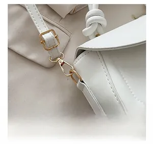 Detail of white lychee leather texture and gold metal hardware with knotted strap