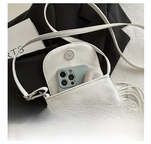 Detalle de bandolera blanca de cuero con espacio para el teléfono móvil y el pintalabios
