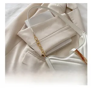 Detail of white quilted leather bag with V-pattern stitching and metal chain strap