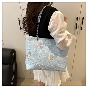 Light blue tote bag with quilted texture, colorful butterfly embroidery and chain strap