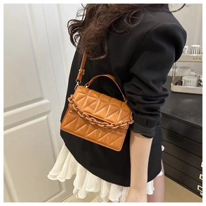 Détail du sac bandoulière matelassé avec chaîne en acrylique orange et poignée