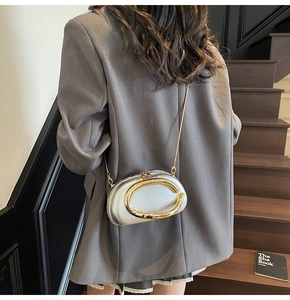 Detail of silver metallic mini bag with gold C-buckle and elegant chain strap on a blazer