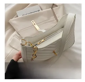 Detail of white quilted underarm bag featuring a gold chain and smooth metal zipper