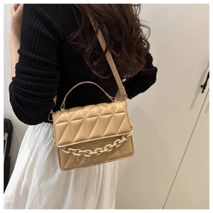 Détail du sac à main beige matelassé avec chaîne décorative et texture raffinée