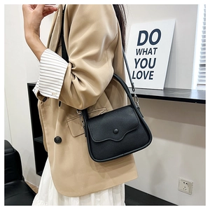Detail of black lychee grain leather mini bag showing handheld handle and crossbody strap
