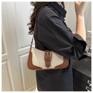 Detailed shot of retro linen and brown leather patchwork shoulder bag with metal buckle