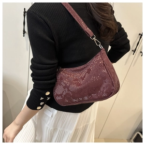 Detail of dark red snakeskin pattern shoulder bag with silver buckle and zipper closure