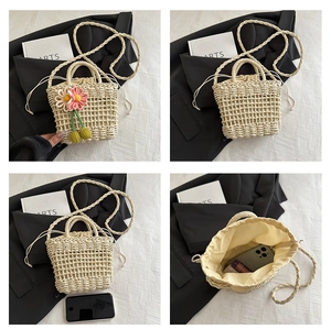 Detail of hollow straw crossbody bag with drawstring liner and flower charm