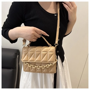 Détail du sac à bandoulière matelassé beige avec chaîne acrylique porté par un mannequin
