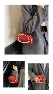 Detail of red mini clutch bag with golden metal handle and crossbody chain strap