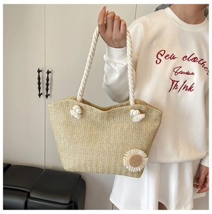 Detail of straw woven tote bag featuring white rope handles and sunflower decoration