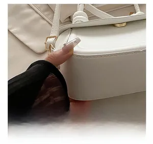Detail of white saddle bag showing gold buckle and precision stitching on leather