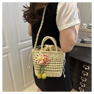 Detail of hand-woven straw bag with crochet flowers and drawstring lining on a model