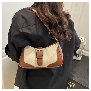 Detail view of retro canvas and brown leather patchwork bag with silver buckle