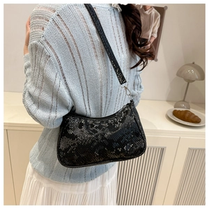 Sac baguette chic à imprimé serpent porté sous le bras avec une tenue d'été