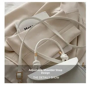 Detail of adjustable strap with light gold buckle and knot handle on a white handbag