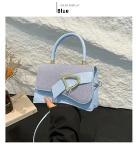 Detailed view of blue striped handbag flap and elegant gold D-shaped metal buckle