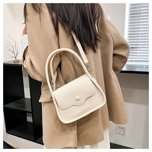 Close-up of cream litchi texture leather handbag with wavy flap and round buckle detail