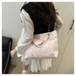 Detail of pink tote bag showing embossed fabric texture and colorful butterfly embroidery