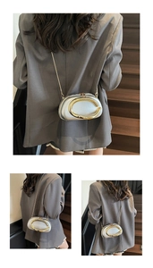 Macro detail of silver clutch bag with horseshoe buckle and sleek gold chain strap