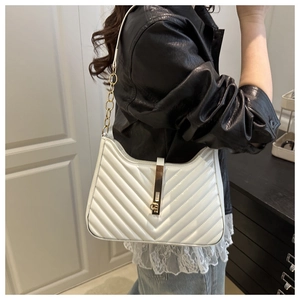 Detail of white chevron quilted leather shoulder bag with gold chain and clasp closure