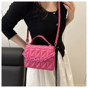 Détail d'un sac matelassé rose vif avec chaîne acrylique et finitions dorées