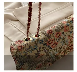 Detailed close-up of golden metal eyelet and floral jacquard texture on vintage chain bag