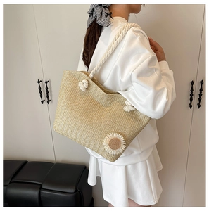 Detail of handwoven straw tote featuring a 3D daisy applique and white rope handles